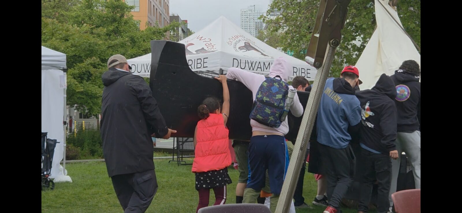 Children working on the Makah-style whaling canoe at the Duwamish Tribe tent, NW Folklife